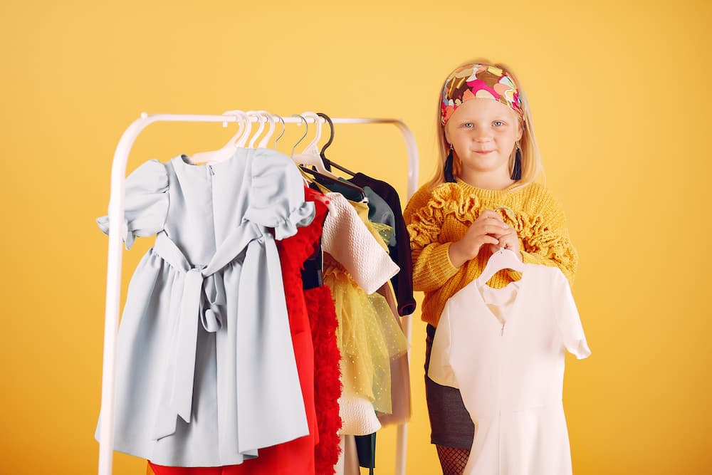 Menina bonitinha com sacos de compras em um fundo amarelo